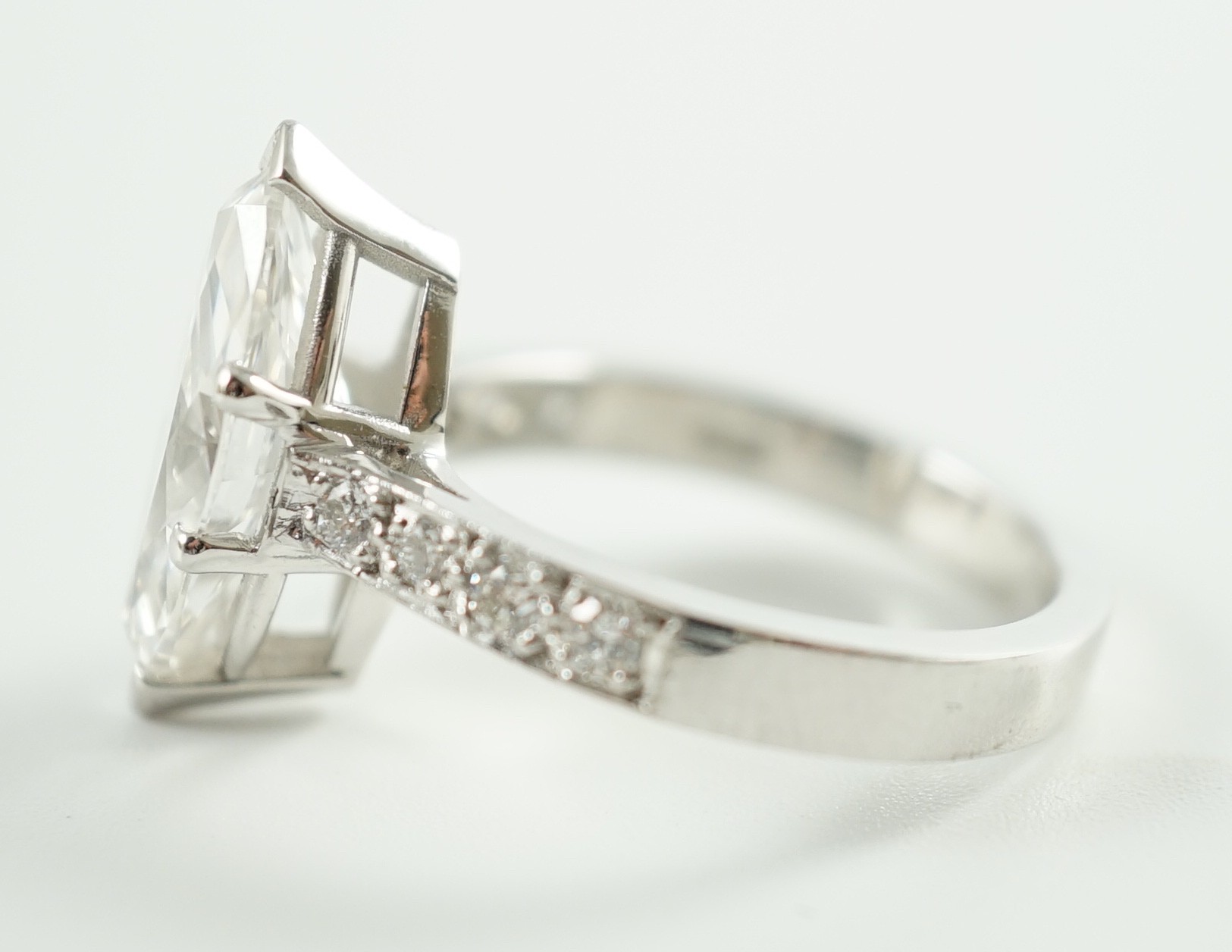 A modern 18ct white gold and single stone marquise diamond set dress ring, with graduated diamond set shoulders, with accompanying WGI report dated 18/6/2021, stating the stone to weigh 3.70ct